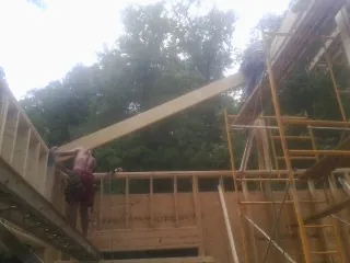 Carpenter raising a rafter beam on a new second story frame in Leesburg